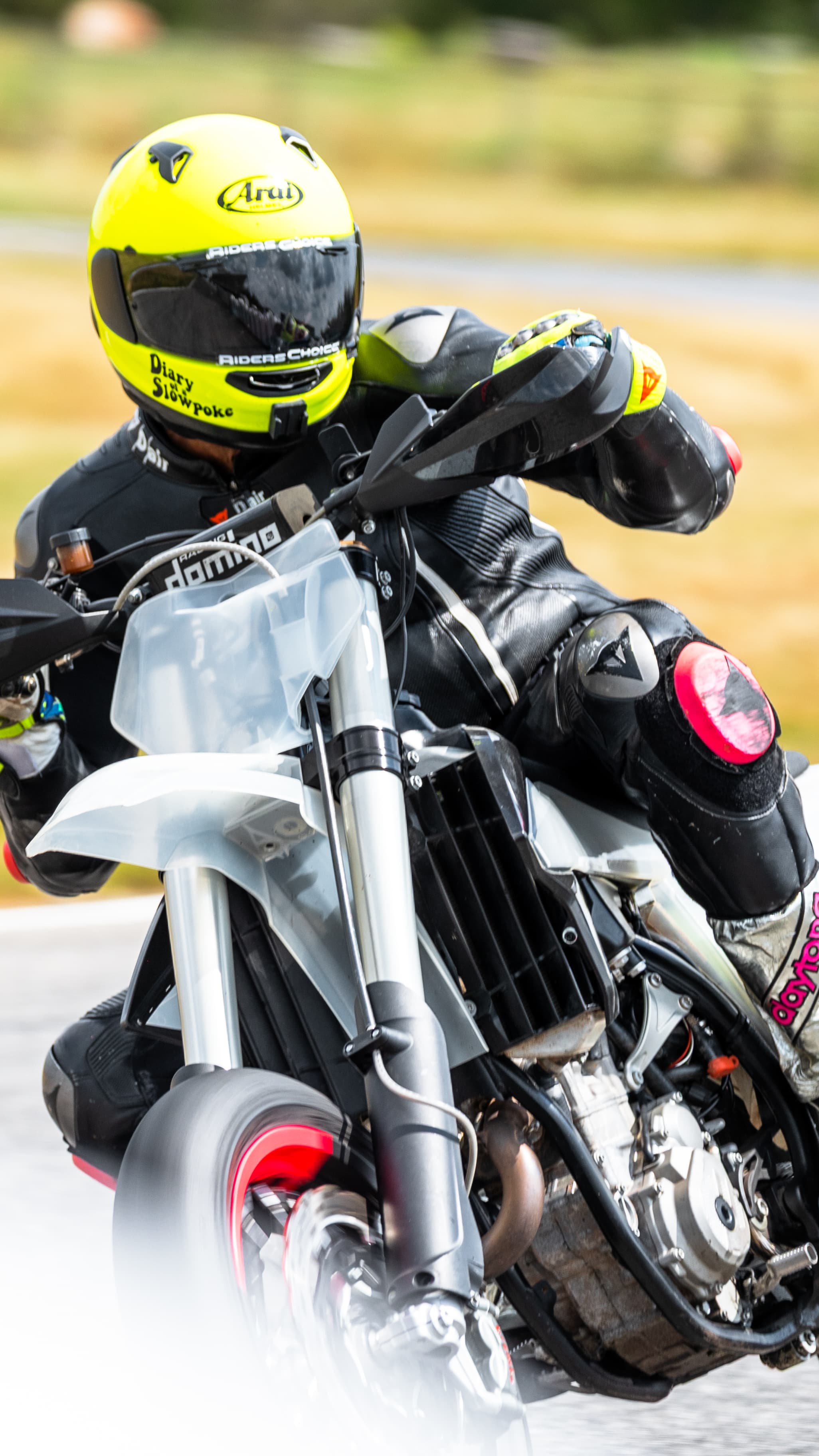 Close view of a yellow-helmeted supermoto rider cornering.