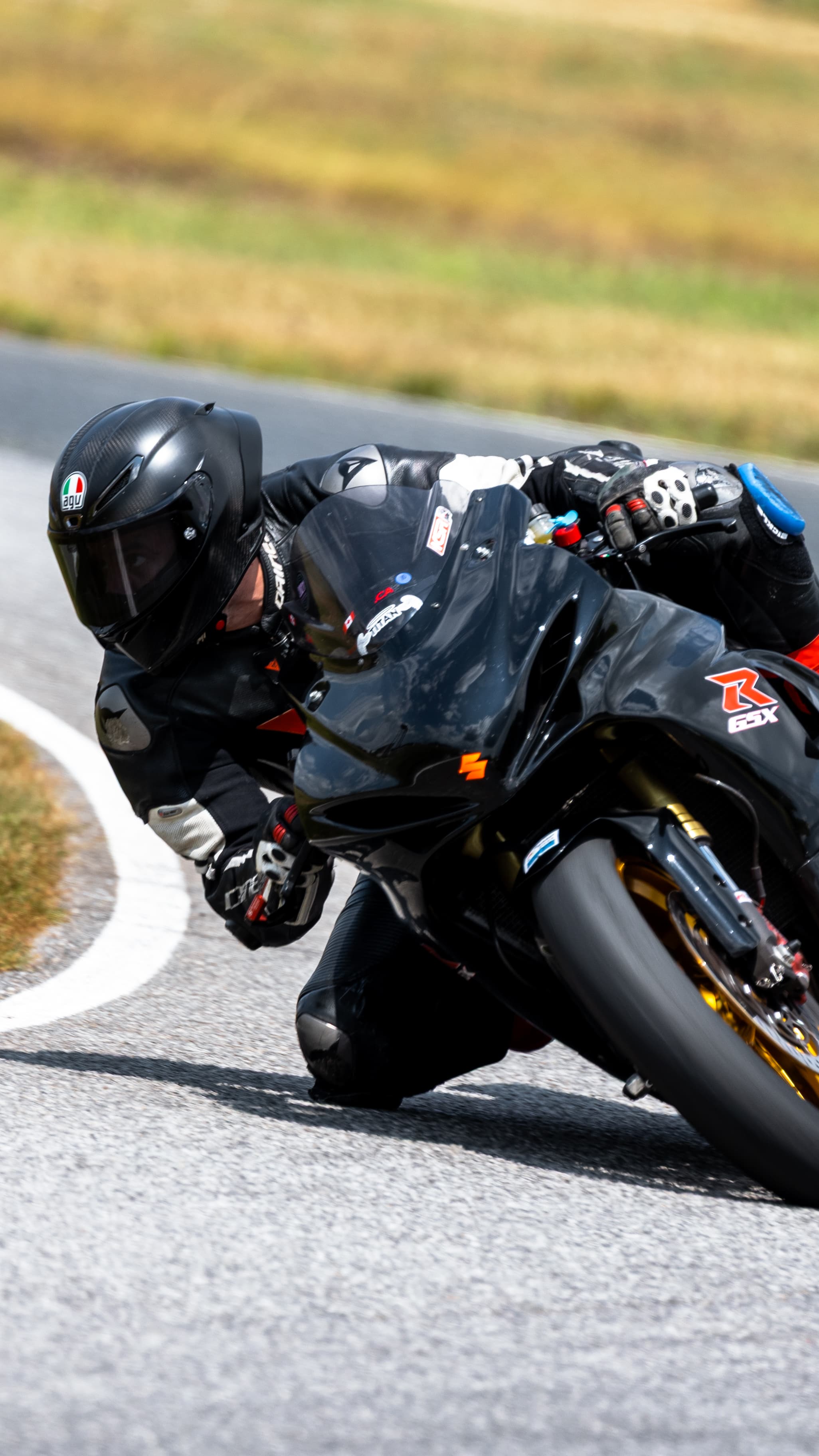 Close view of a rider leaning a black Suzuki into a turn.