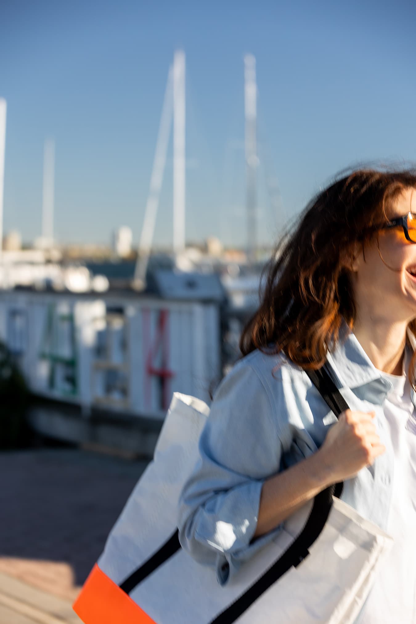 A candid close view of a model carrying a Dayshaped tote at the marina.