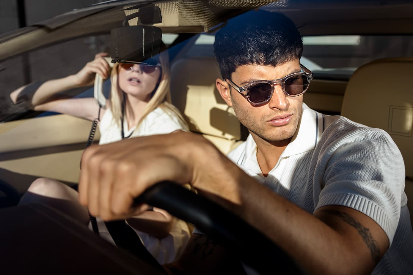 Two models wearing Waid sunglasses photographed through a Ferrari windscreen.