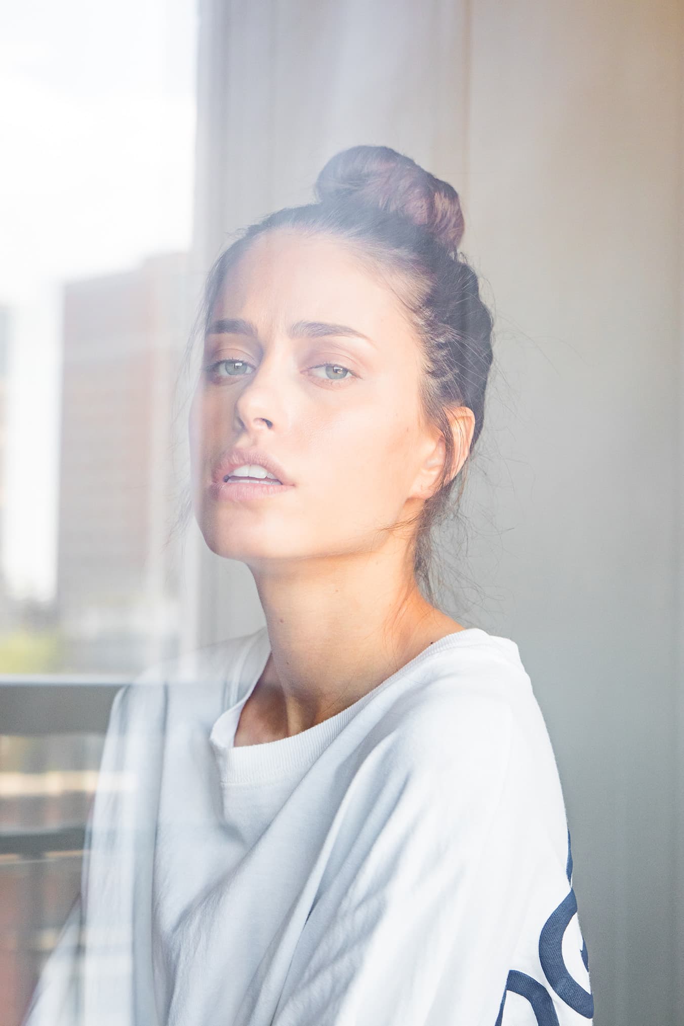 Portrait of Chloe looking upward through reflective window glass.