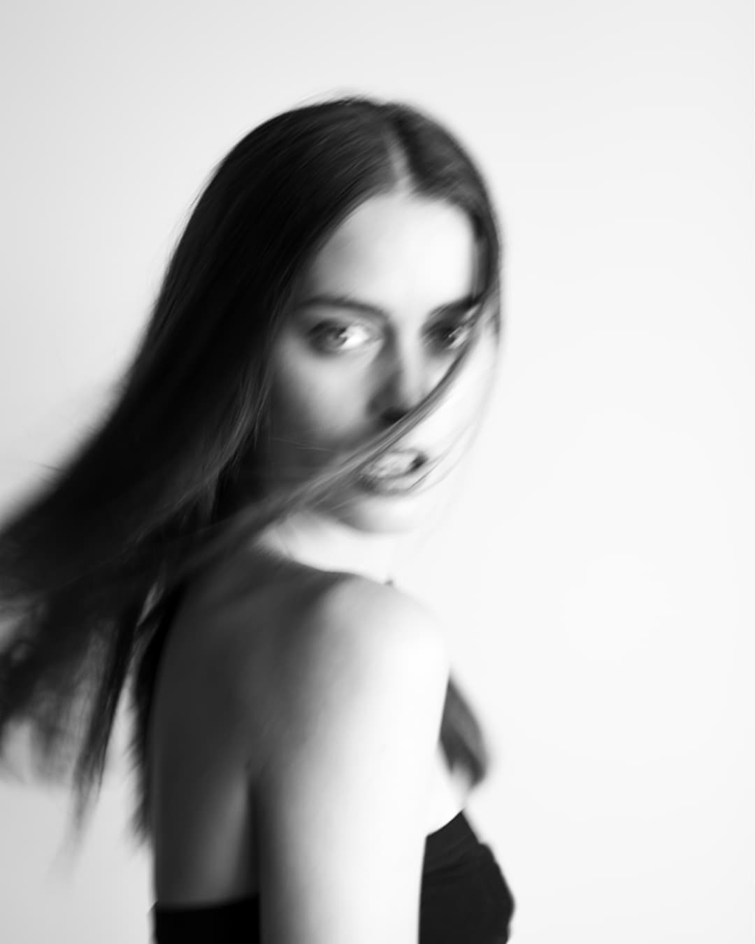 Black-and-white portrait of Chloe turning toward the camera, with motion blur through her hair.