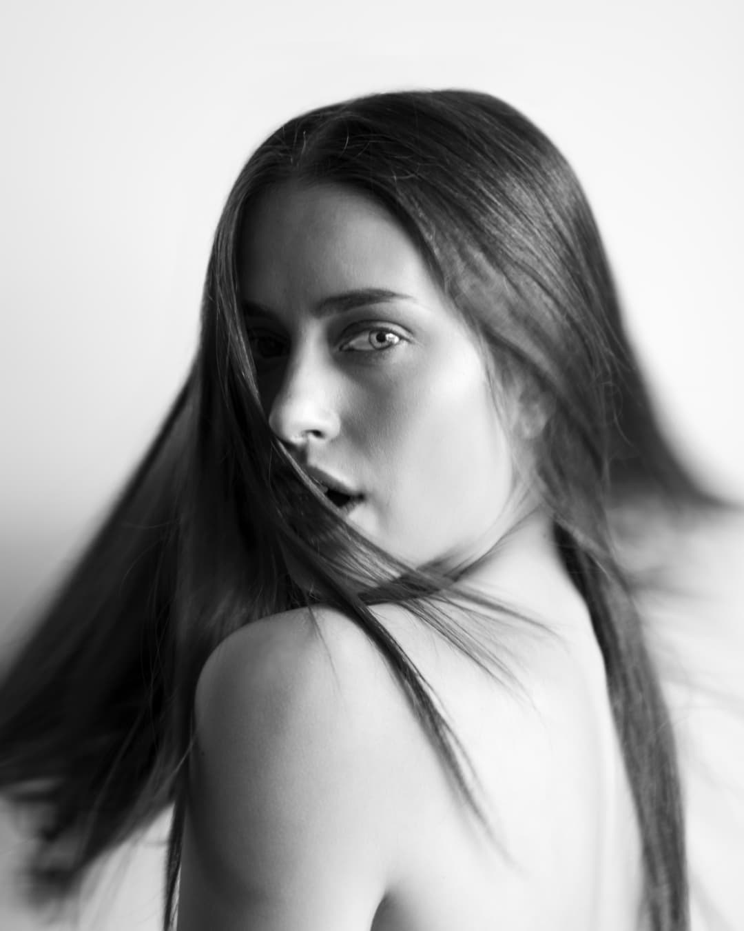 Black-and-white portrait of Chloe looking over her shoulder with hair sweeping across her face.