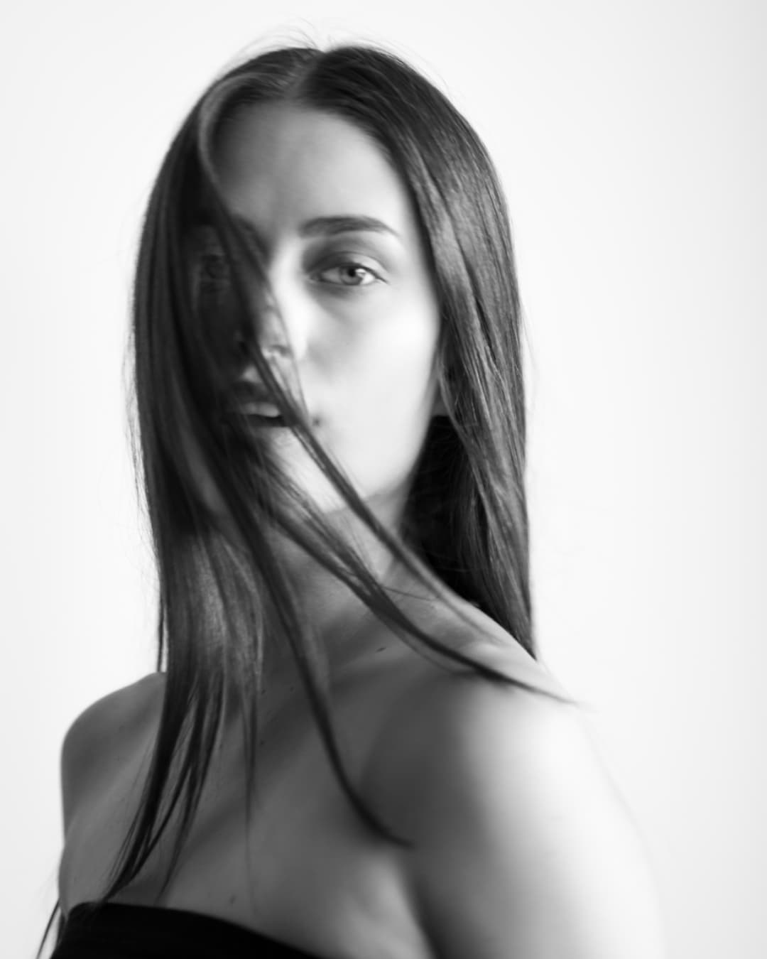 Black-and-white portrait of Chloe with loose hair moving across her face.