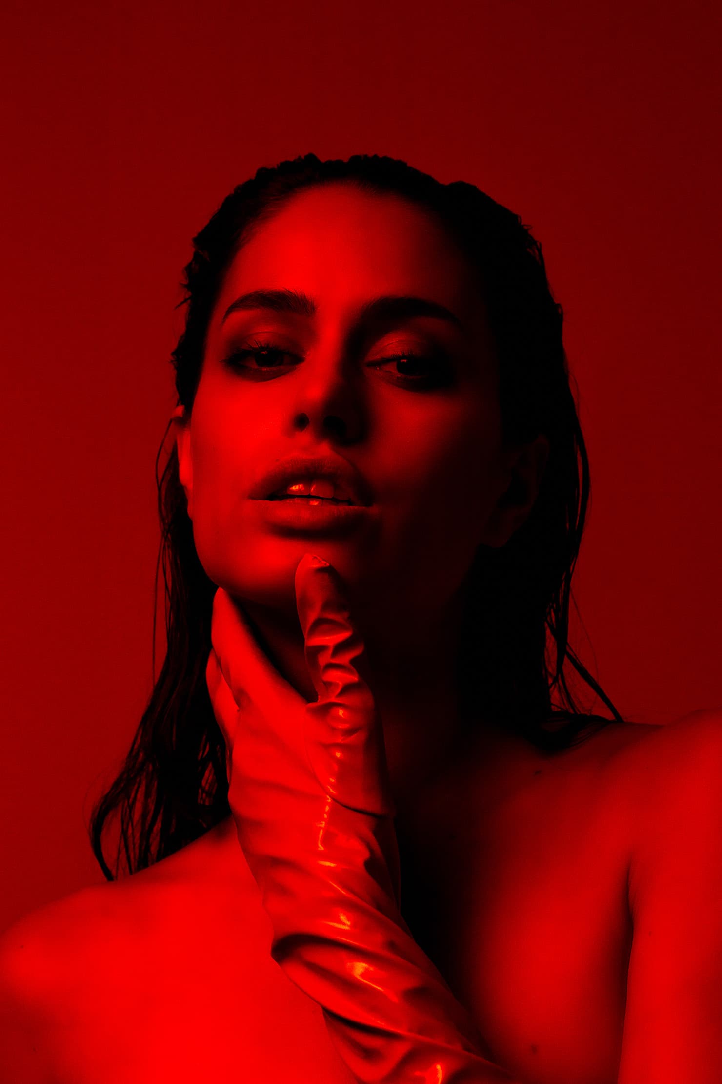 Red-lit portrait of Chloe with a satin-gloved hand beneath her chin.