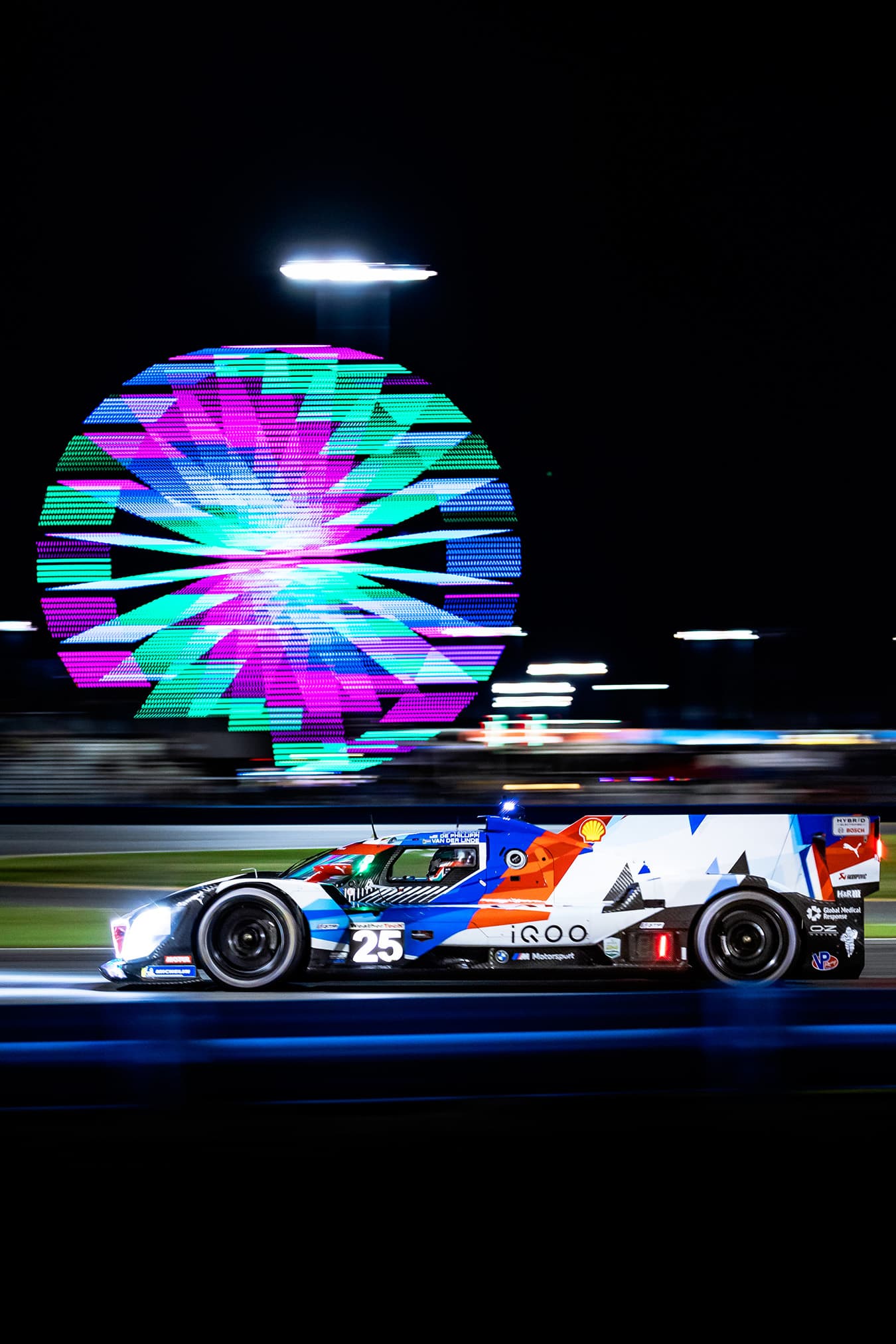 A BMW prototype beneath a colourful Ferris wheel at night.