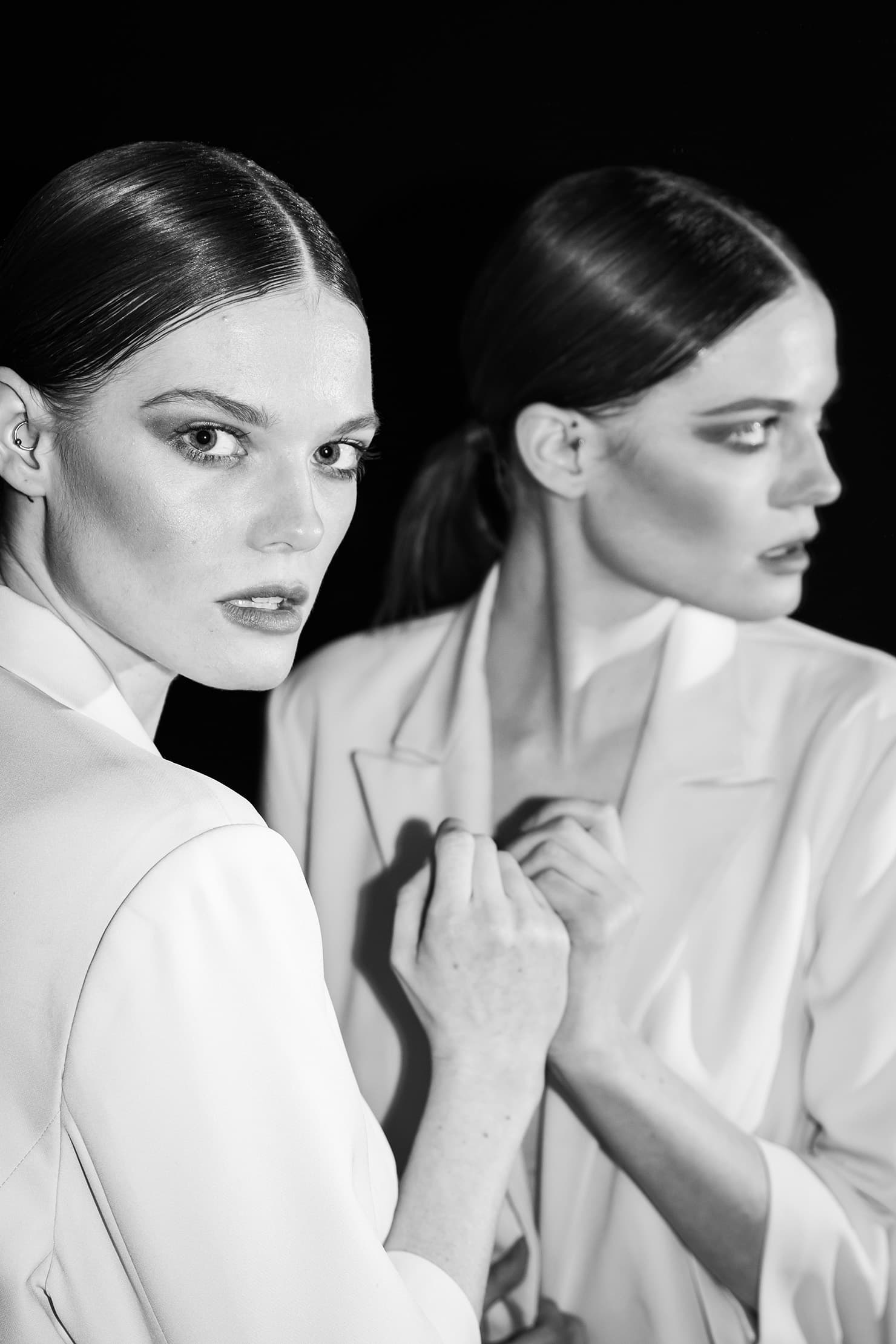 Close black-and-white portrait of a model and her reflection.