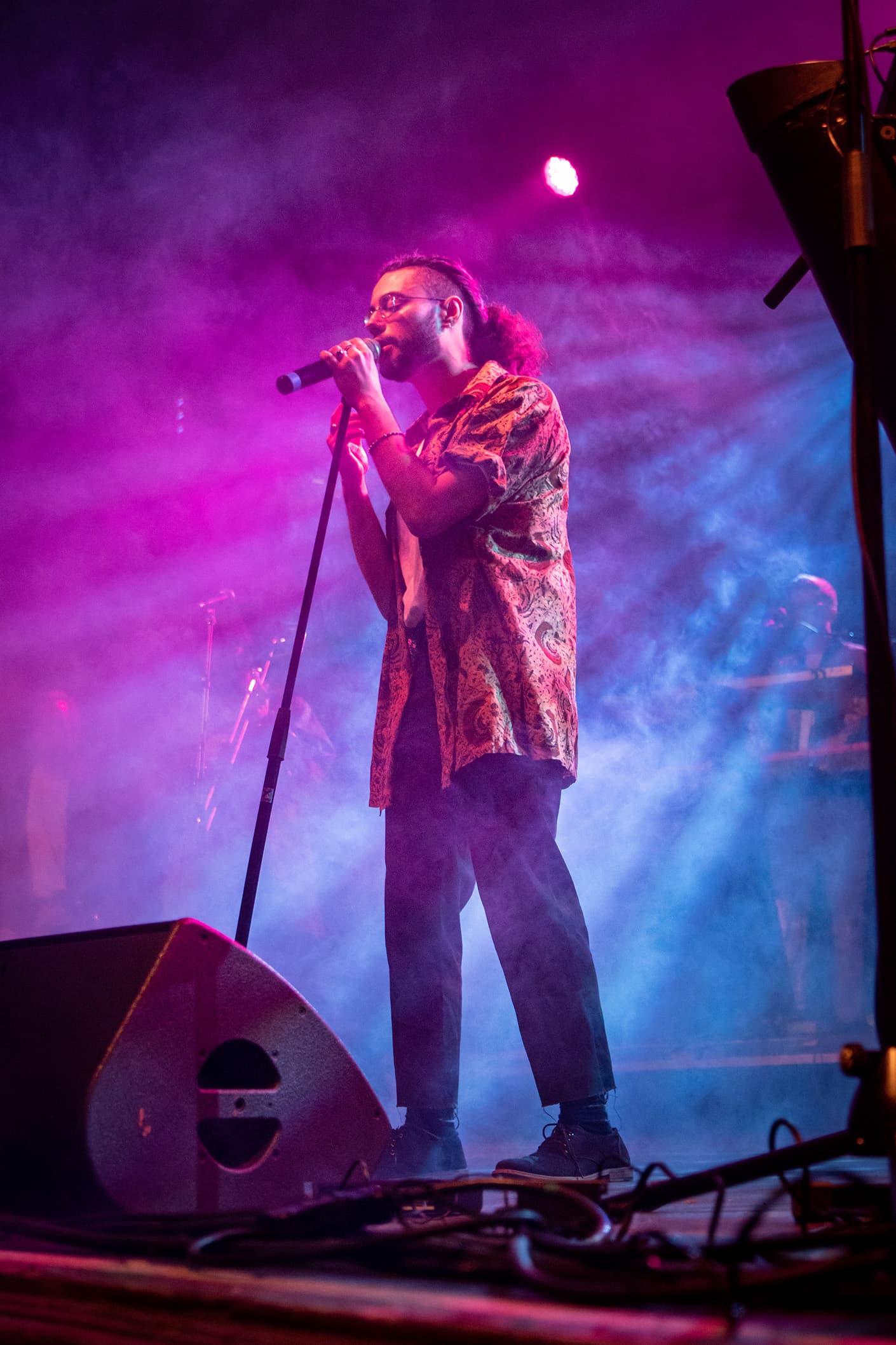 A singer performing under purple and blue stage lighting.