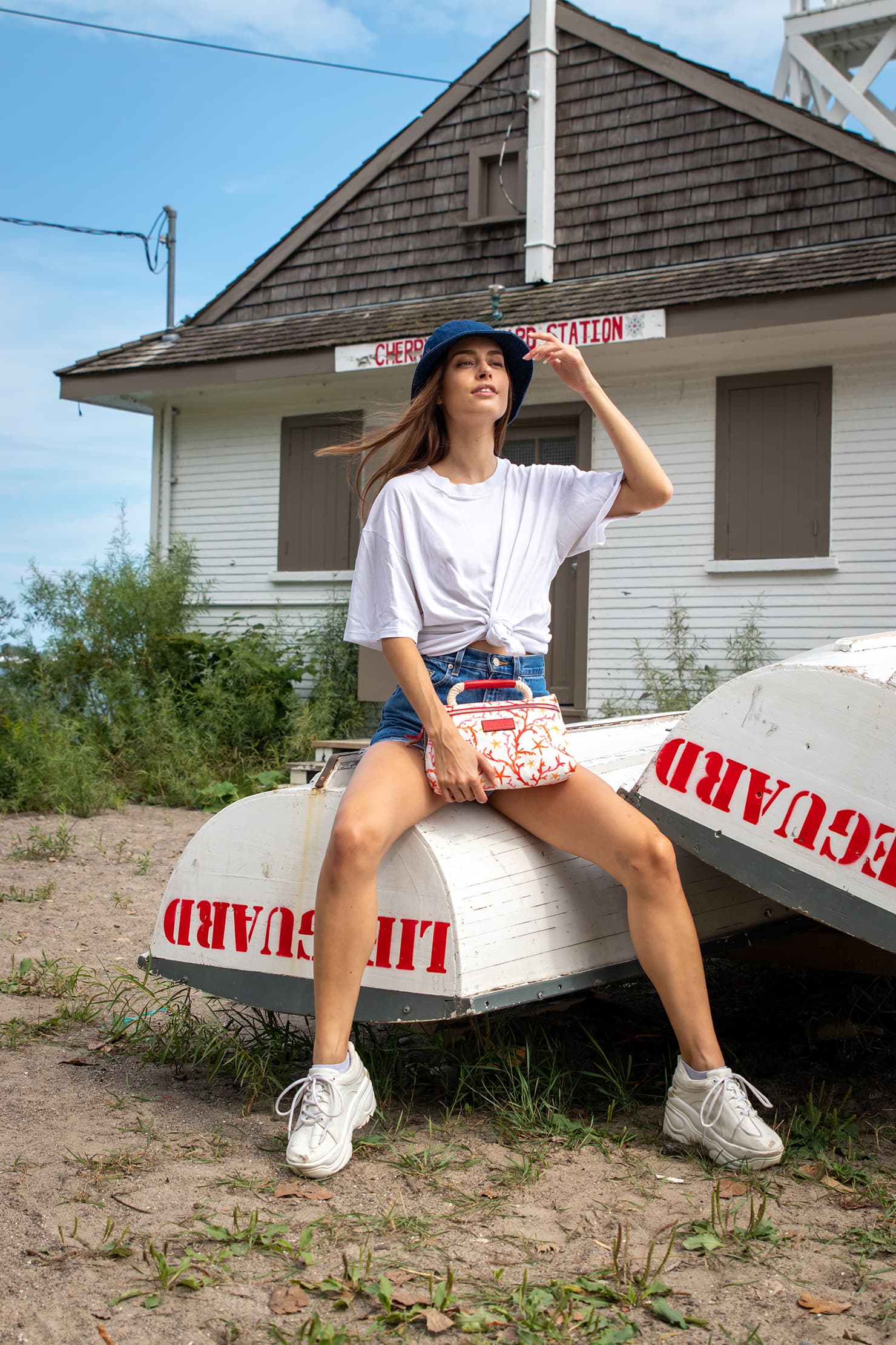 A model seated on an upturned lifeguard boat.