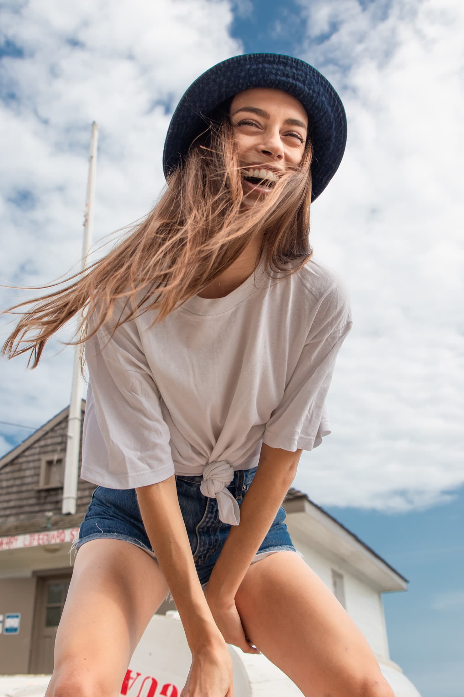A model laughing in the wind beside a lifeguard station.
