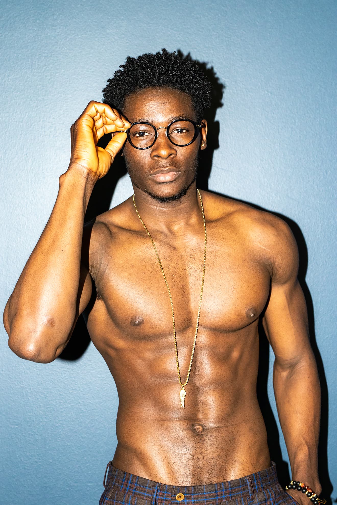 Direct-flash portrait of a man adjusting round glasses.
