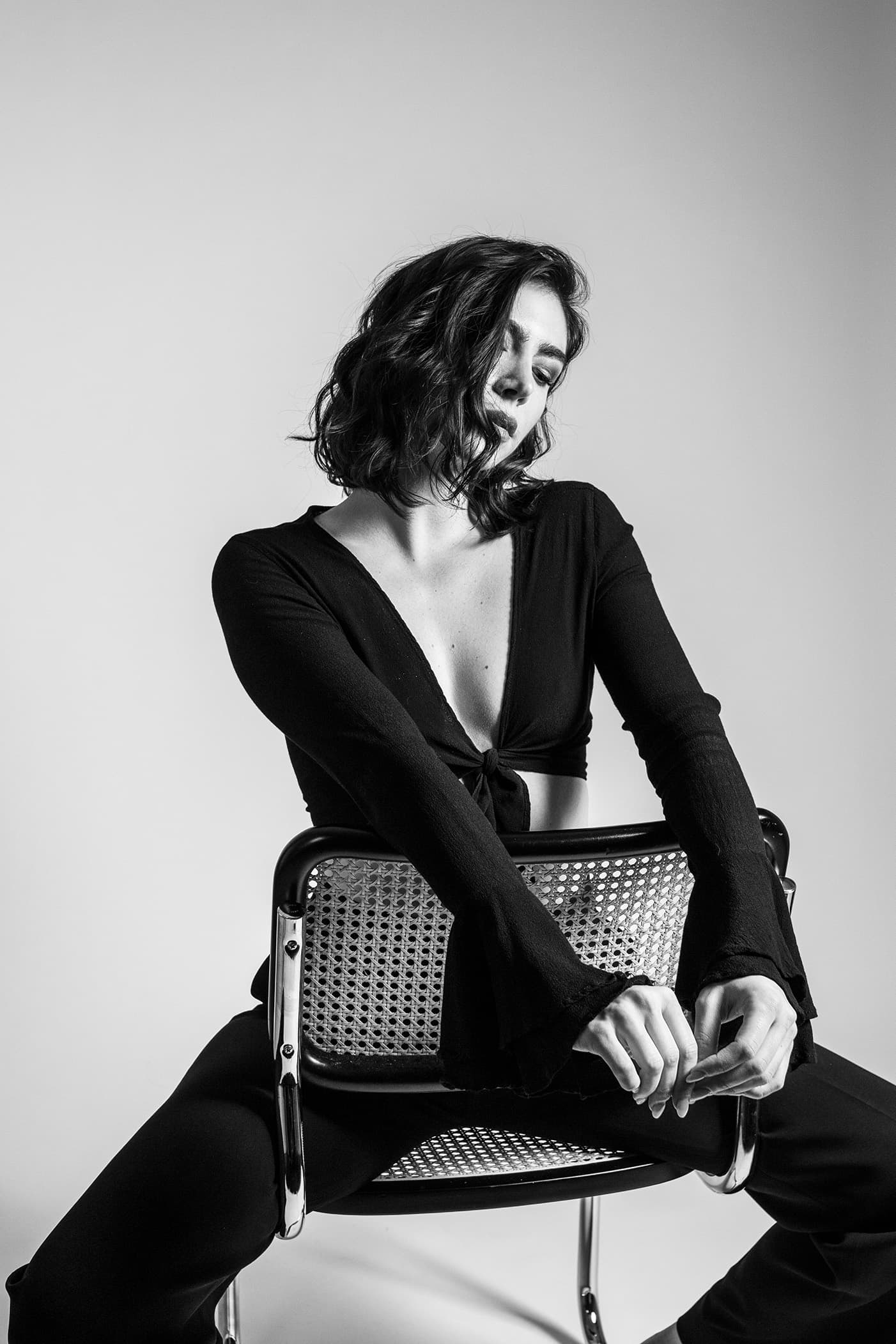 Black-and-white portrait of a model leaning over a chair.