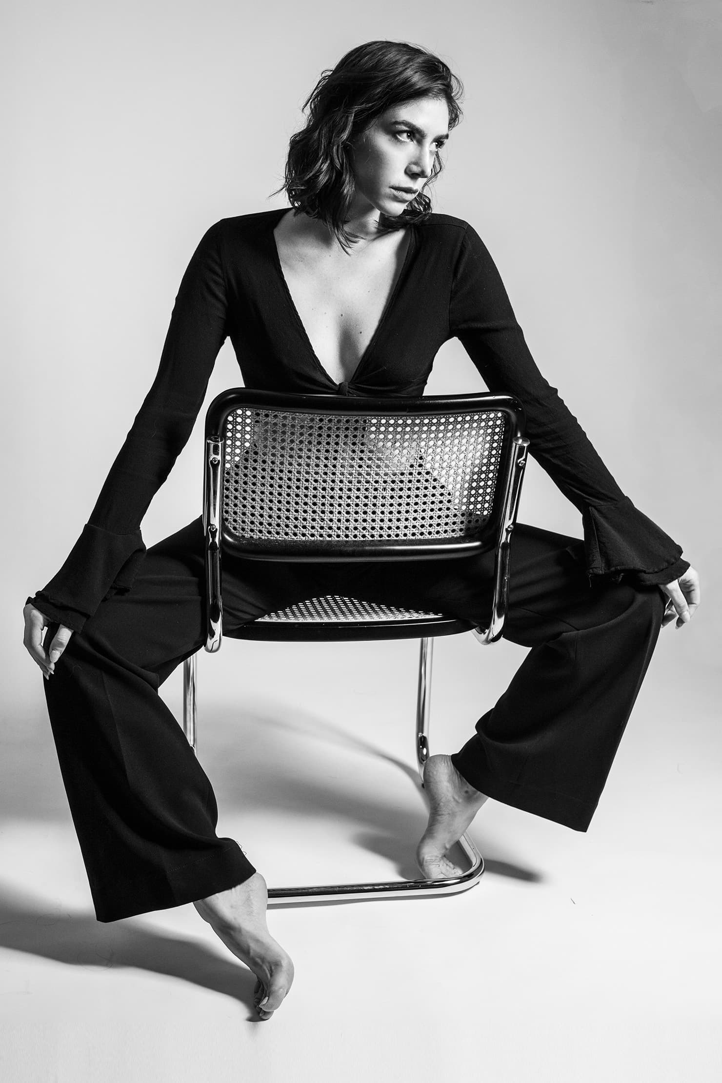 Black-and-white portrait of a model looking aside while seated on a chair.